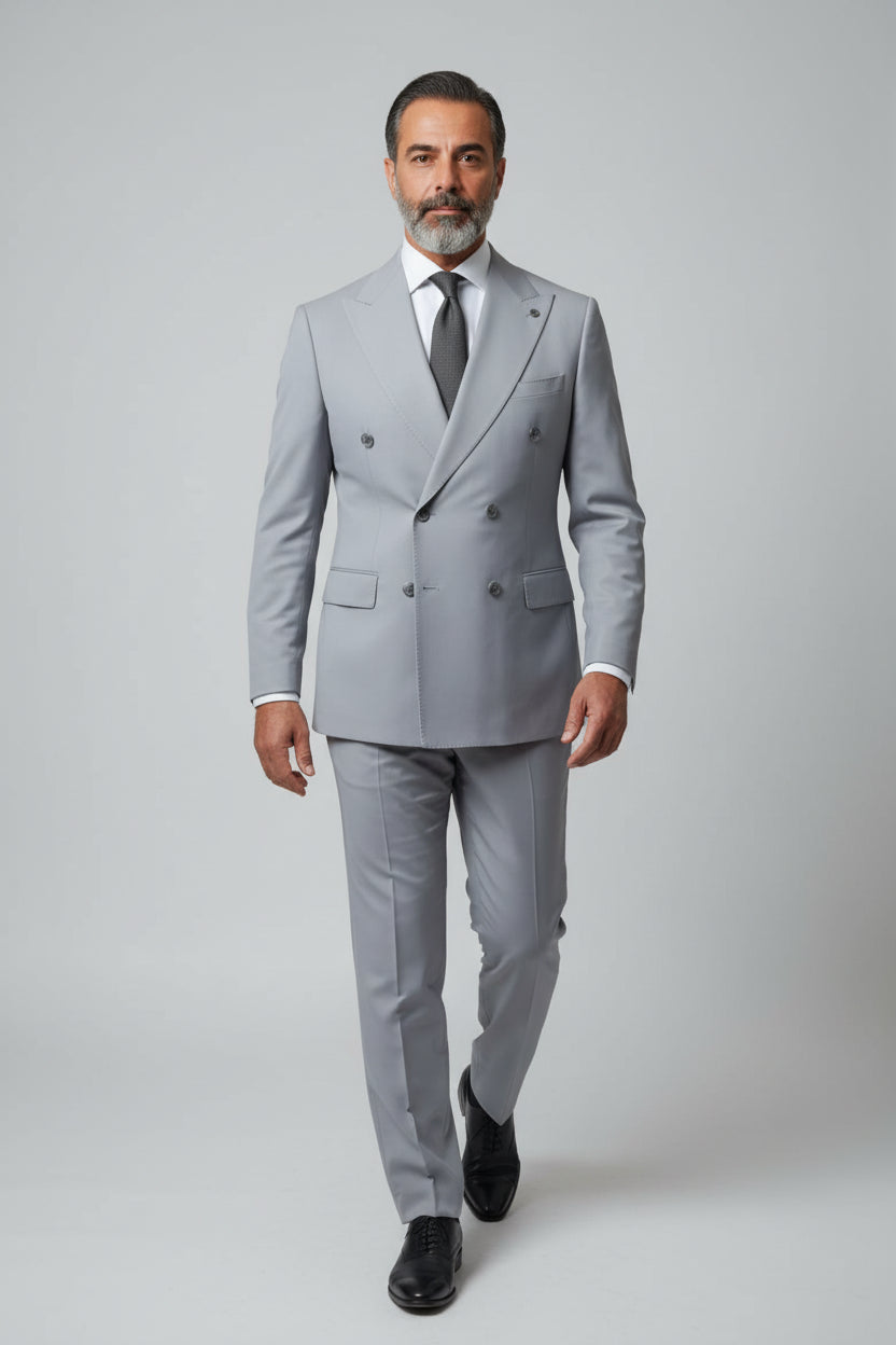 Man wearing light grey double-breasted suit with peak lapels and tailored fit.