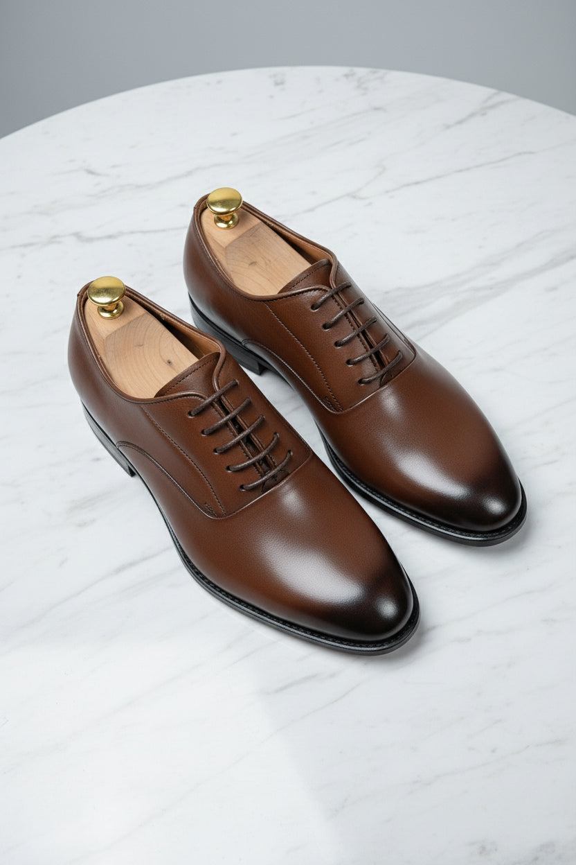 Brown leather classic derby shoes with lace-up design on marble surface.