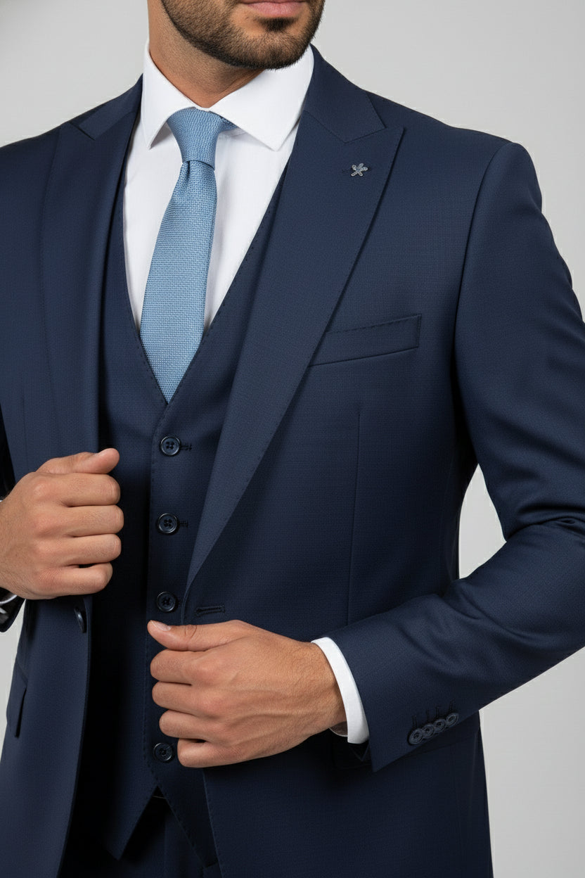 Man wearing black tailored suit with satin lapels and light blue tie.