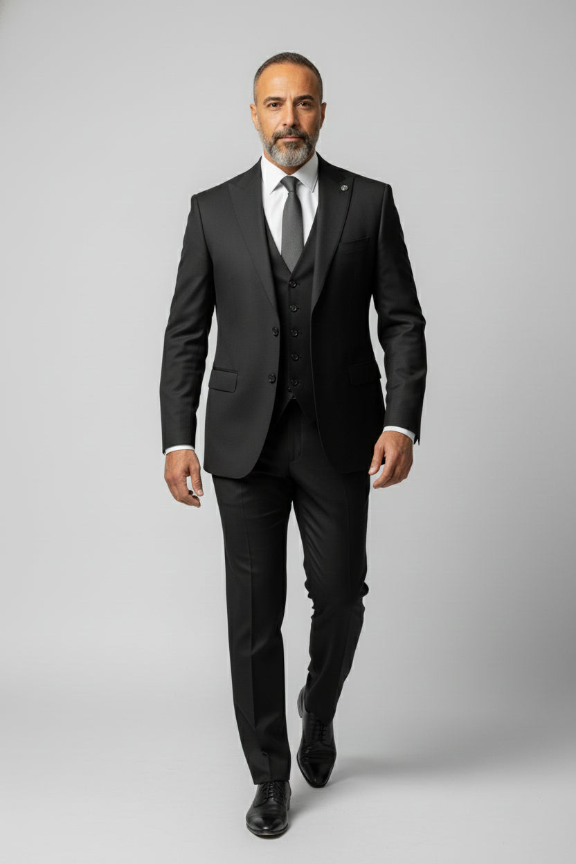 Man wearing black peak lapel three-piece suit with tailored fit for formal events.