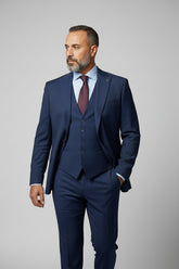Man wearing navy slim fit three-piece suit with matching vest and tie.