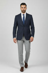 Man wearing navy slim fit two-button suit with grey dress pants and brown shoes.