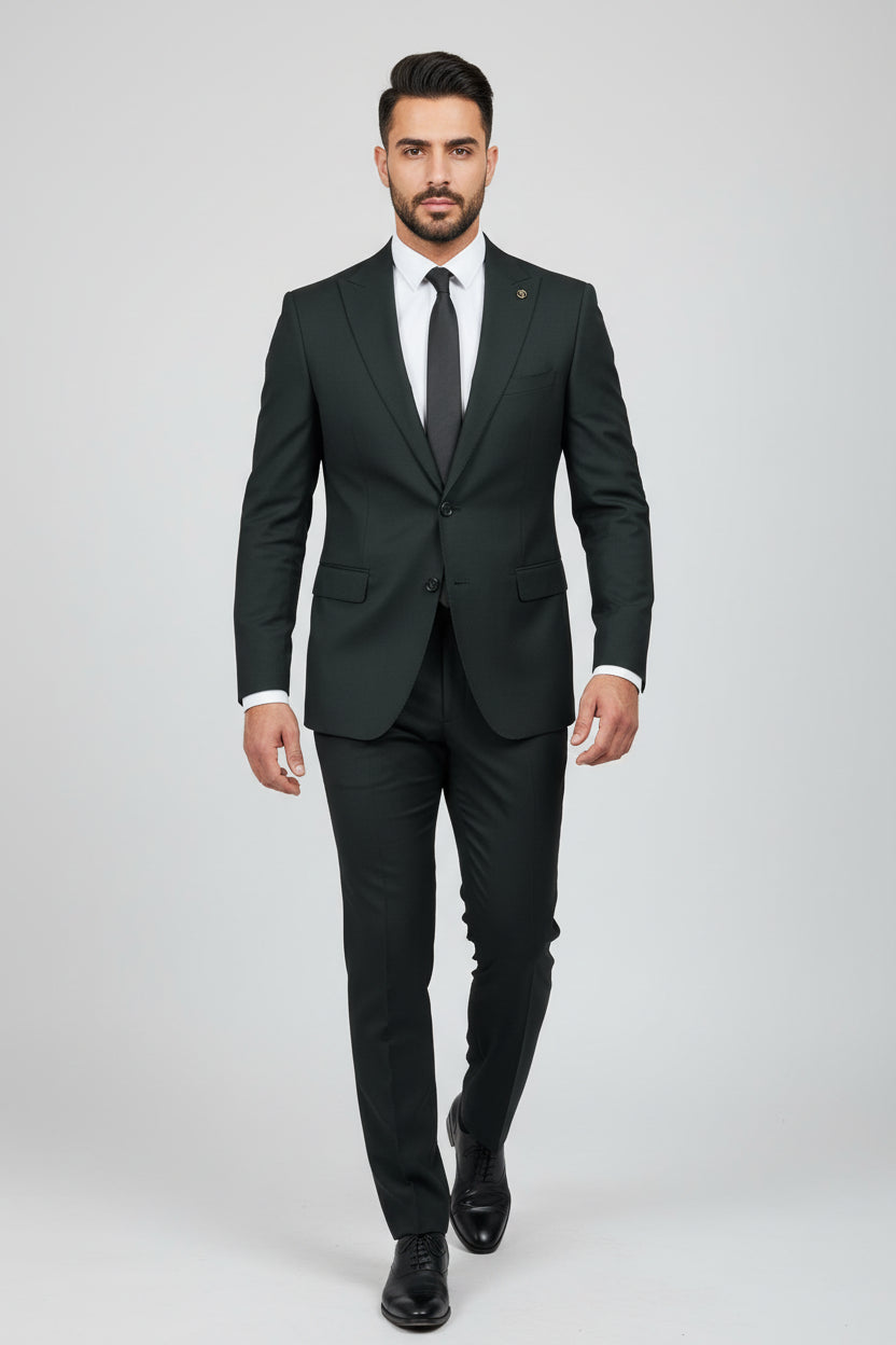 Man wearing dark green tailored two-piece suit with peak lapels and black tie.