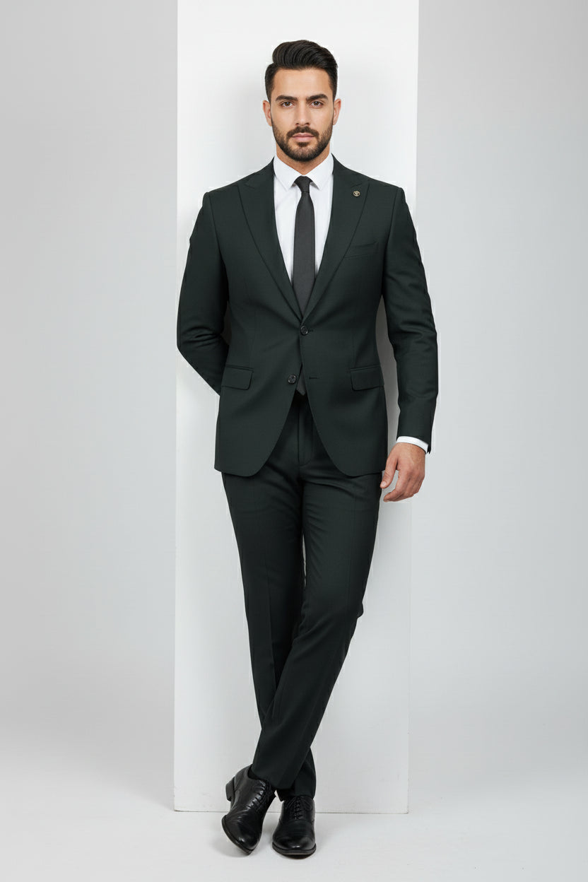 Man wearing dark green tailored two-piece suit with peak lapels and black tie.