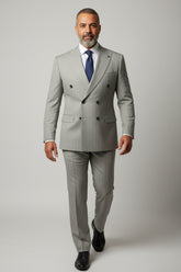 Man in beige double-breasted pinstripe suit with tailored fit and navy tie.
