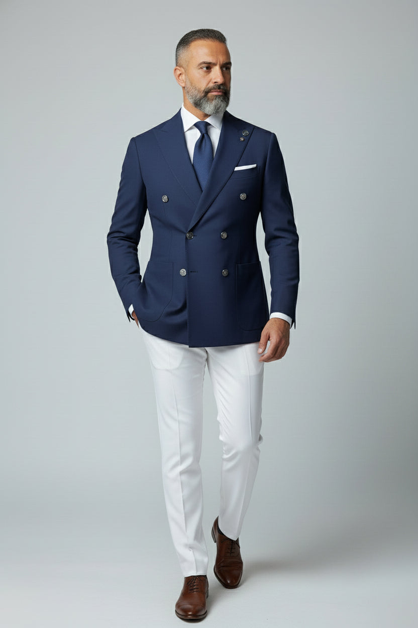 Man wearing navy double-breasted tailored suit set with white trousers.