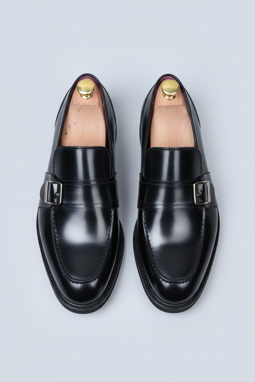 Black leather loafers with silver buckle detail for formal business wear.
