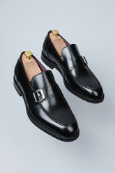 Black leather loafers with silver buckle detail for formal business wear.