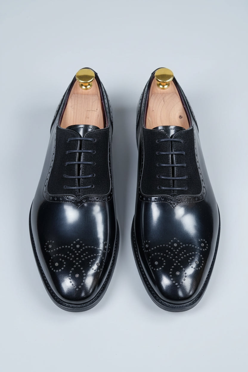 Black brogue Oxford shoes with contrast lining and detailed perforations for formal wear.