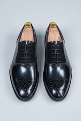 Black brogue Oxford shoes with contrast lining and detailed perforations for formal wear.