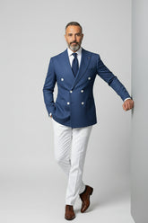 Man wearing blue double-breasted tailored suit with white trousers and brown shoes.