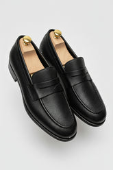 Black textured leather slip-on loafers with elegant design and comfortable fit.