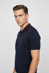 Man wearing navy knit polo with red stripes and slim fit design.