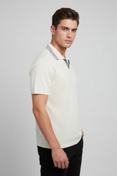 Man wearing white cotton polo shirt with navy stripes on collar, tailored fit.