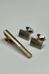 Gold tie clip and cufflinks set with modern geometric design for formal wear.