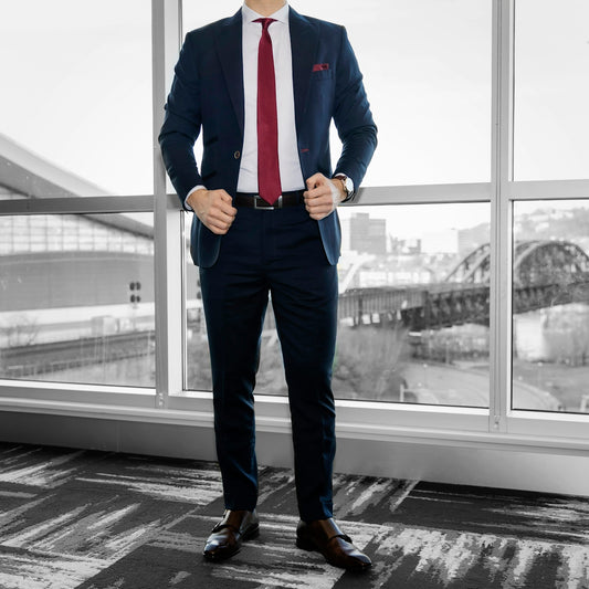 man in blue dress shirt and blue denim jeans standing near glass window