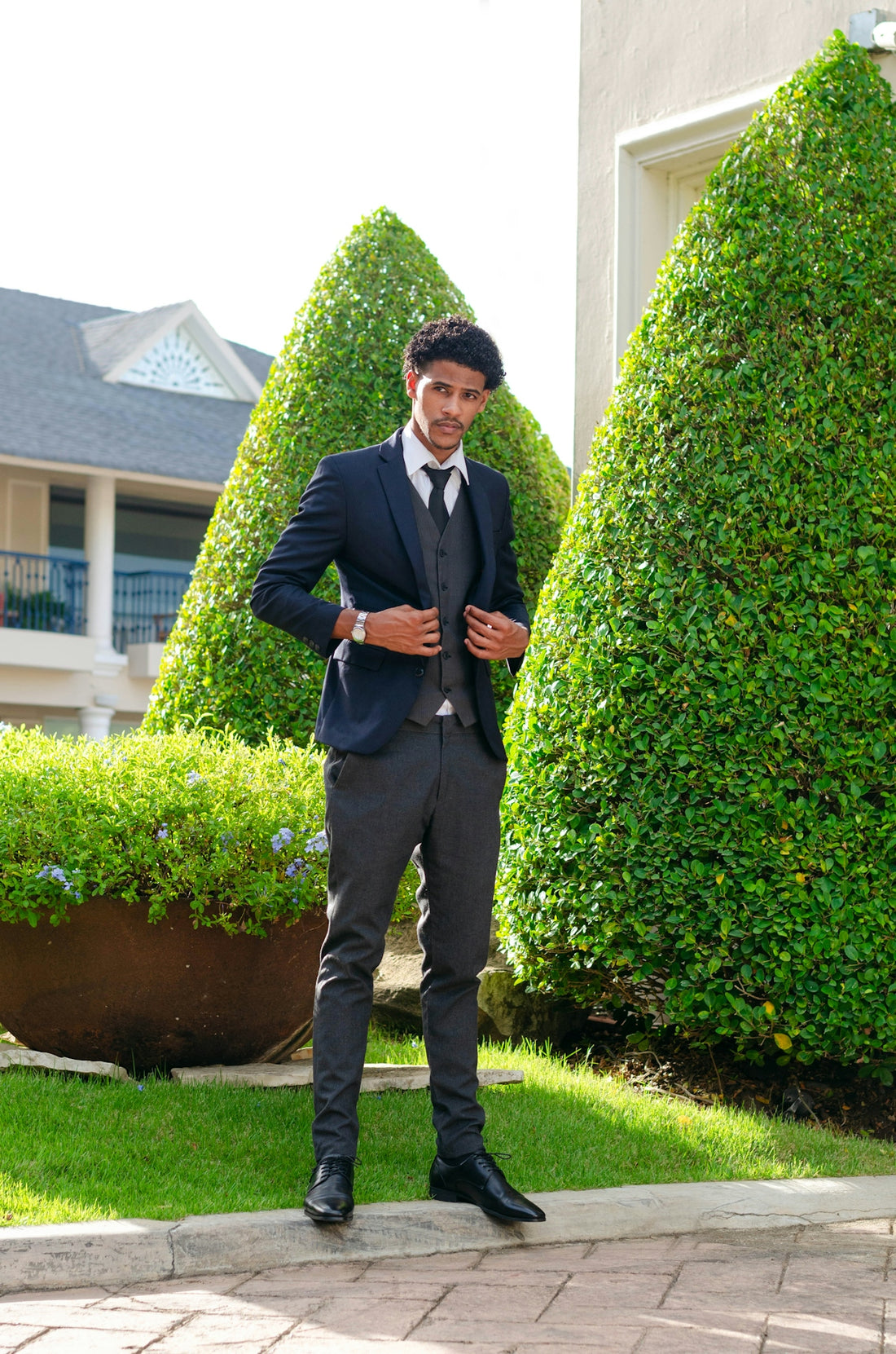 man in black suit standing on green grass field