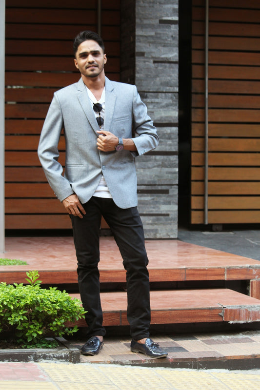 man in gray suit jacket and black pants standing on brown wooden stairs