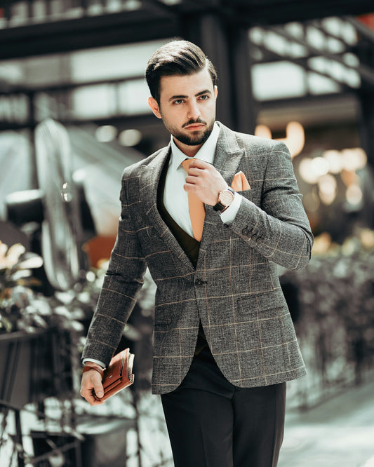 man in black suit jacket holding his necktie