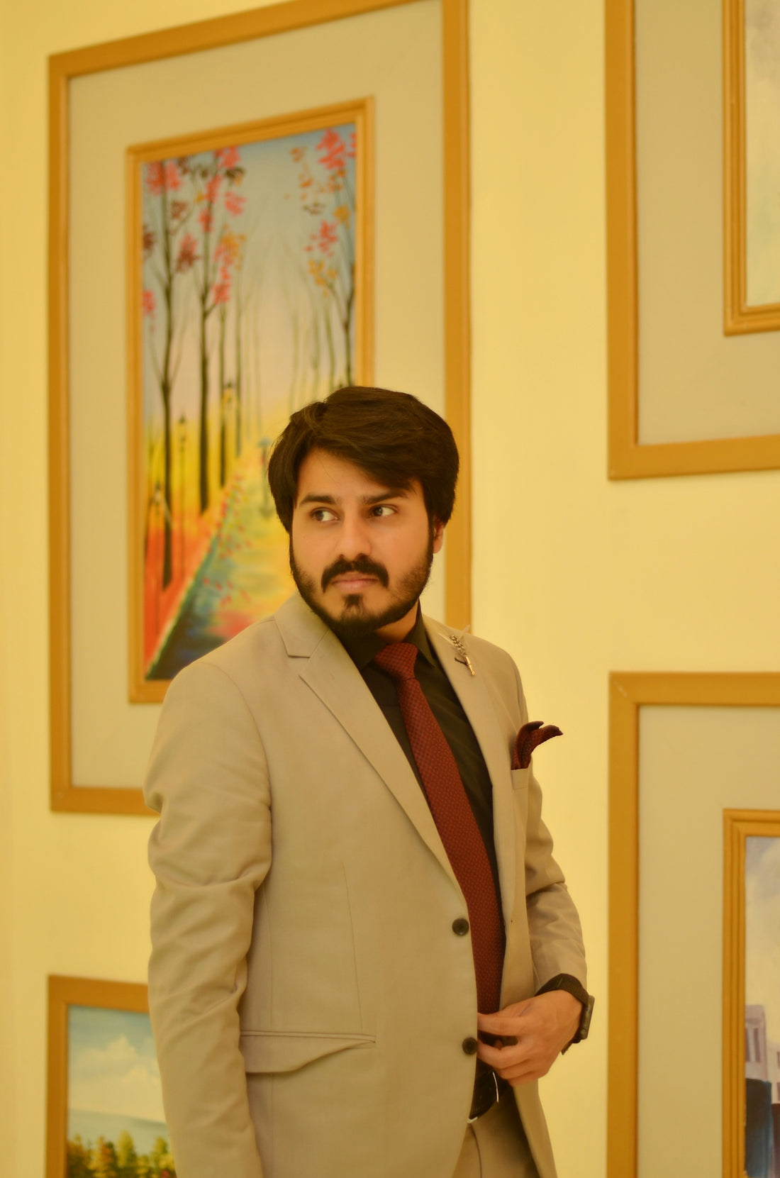 a man in a suit and tie standing in front of paintings