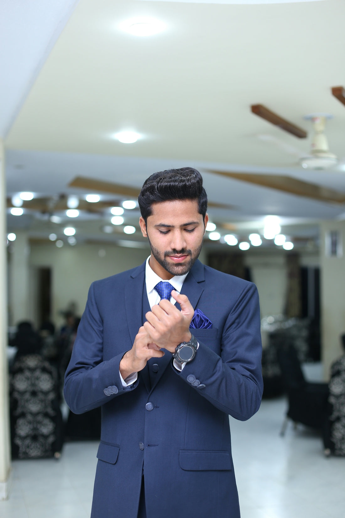 a man in a blue suit is looking at his watch