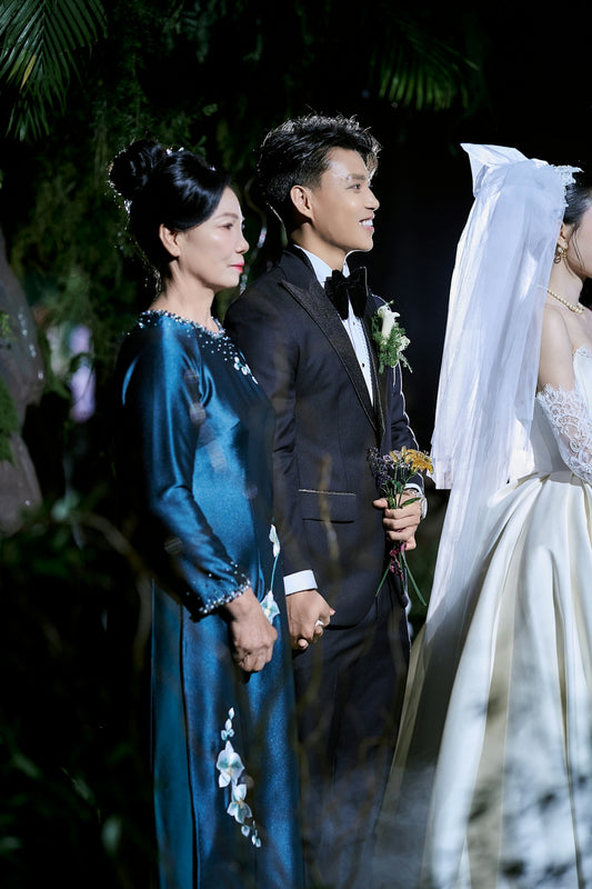 Groom holding hands with his mother at an evening wedding.
