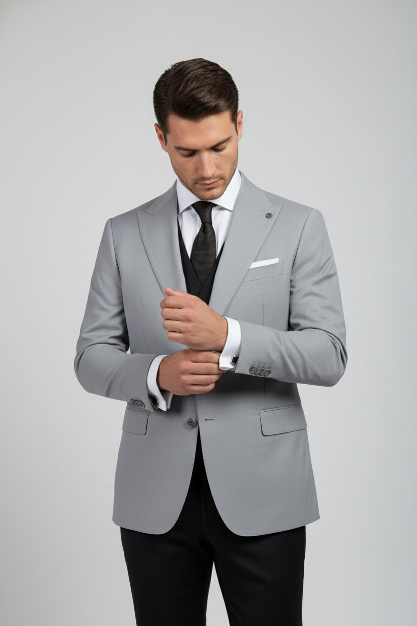 Man adjusting cuffs of light grey double-breasted suit, tailored fit for formal occasions.
