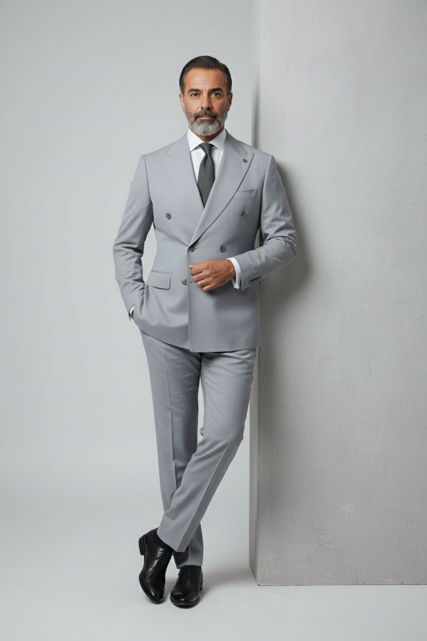 Man wearing light grey double-breasted suit with peak lapels and tailored fit.