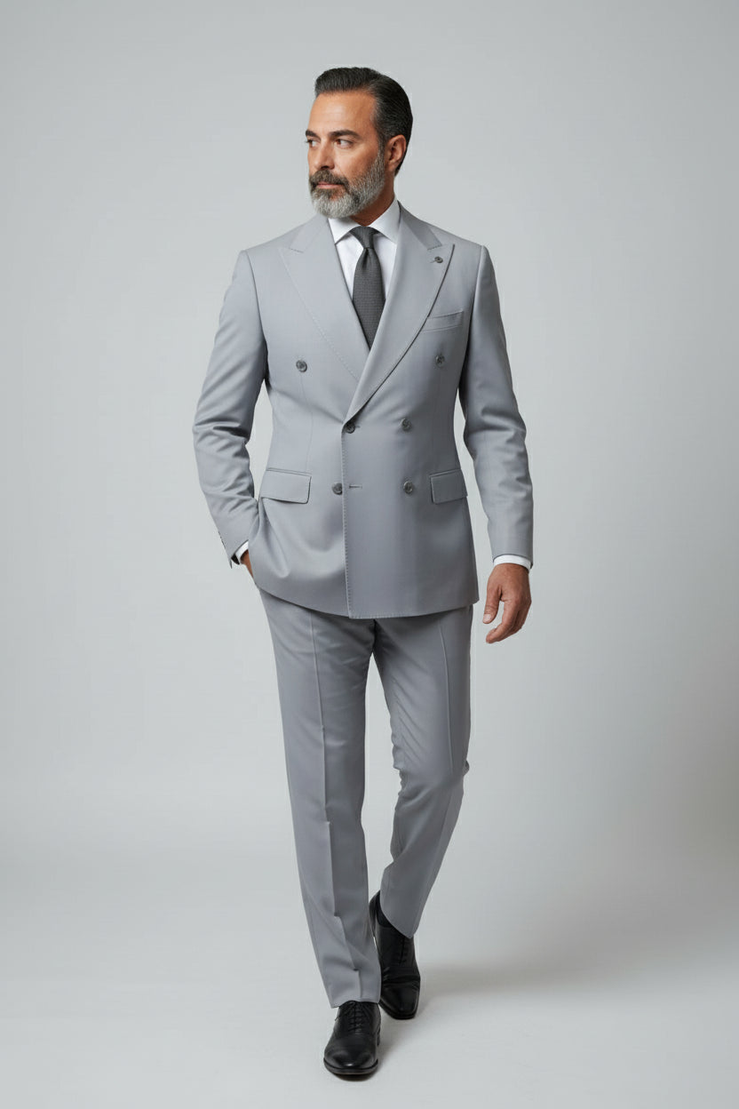 Man wearing light grey double-breasted suit with peak lapels and tailored fit.