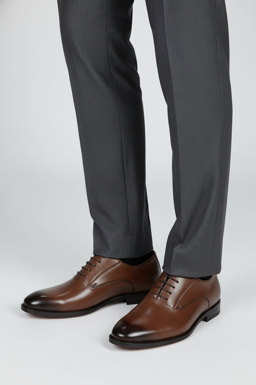 Brown leather classic derby shoes paired with grey tailored trousers.