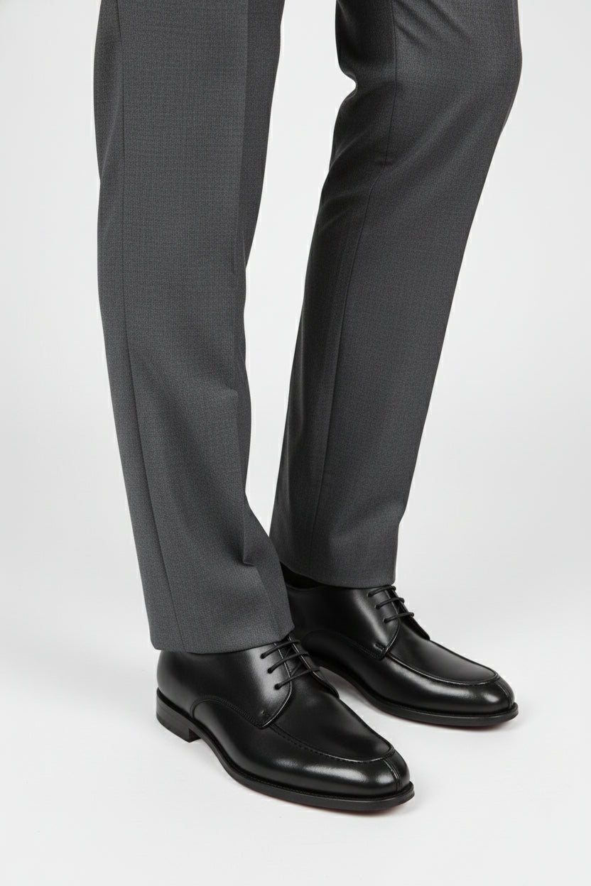 Black leather lace-up dress shoes paired with grey tailored trousers for formal wear.