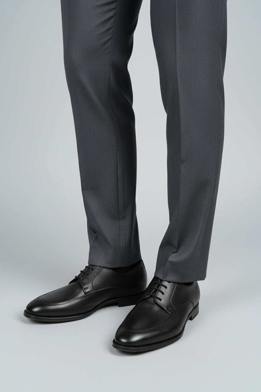 Black leather lace-up dress shoes paired with tailored grey dress pants.