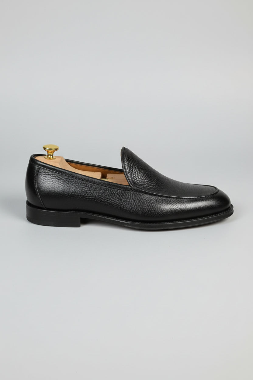 Black leather slip-on loafers with a textured finish for formal and casual wear.
