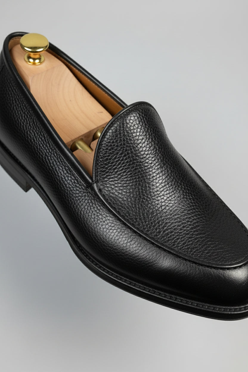 Black leather slip-on loafers with textured finish, ideal for formal or business casual wear.