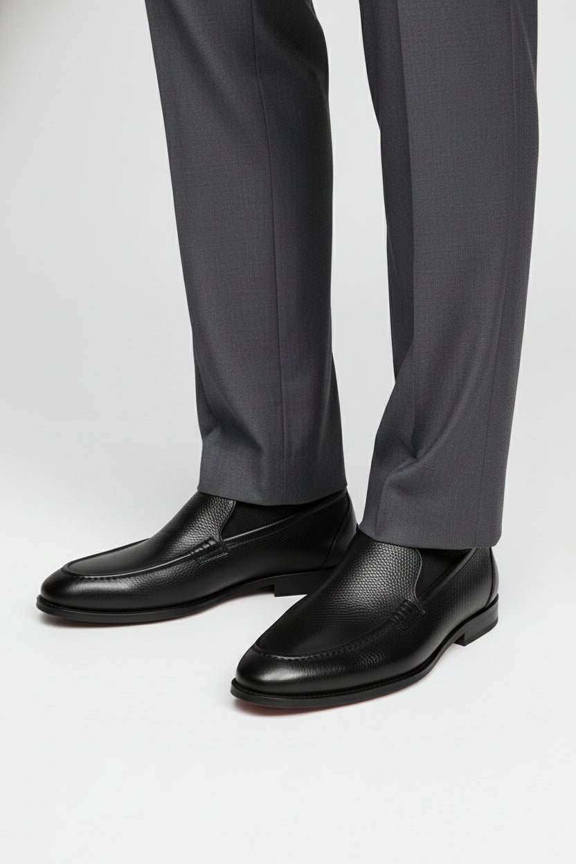 Black slip-on leather tuxedo shoes paired with grey formal trousers.
