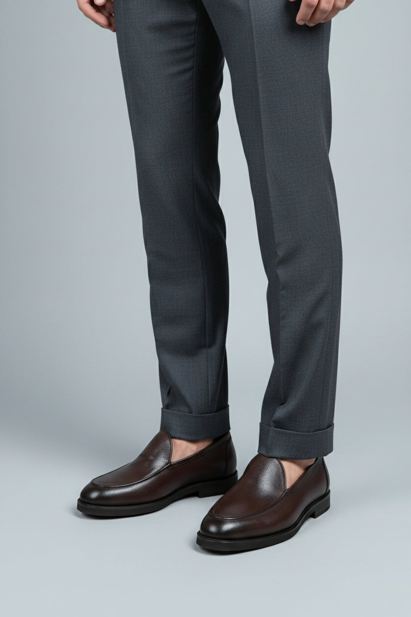 Brown slip-on leather formal shoes paired with tailored grey trousers.
