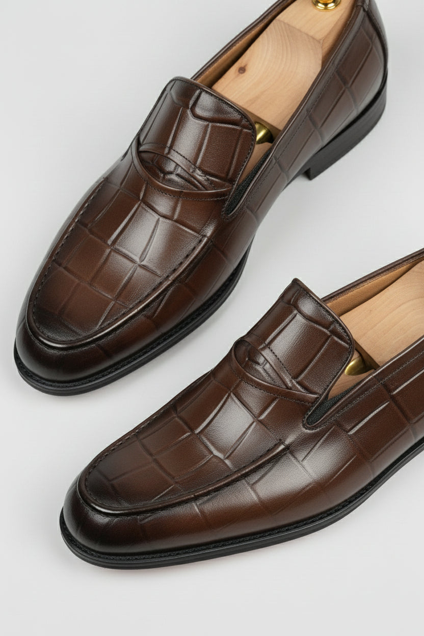 Brown crocodile-embossed slip-on shoes with elegant leather finish for formal wear.