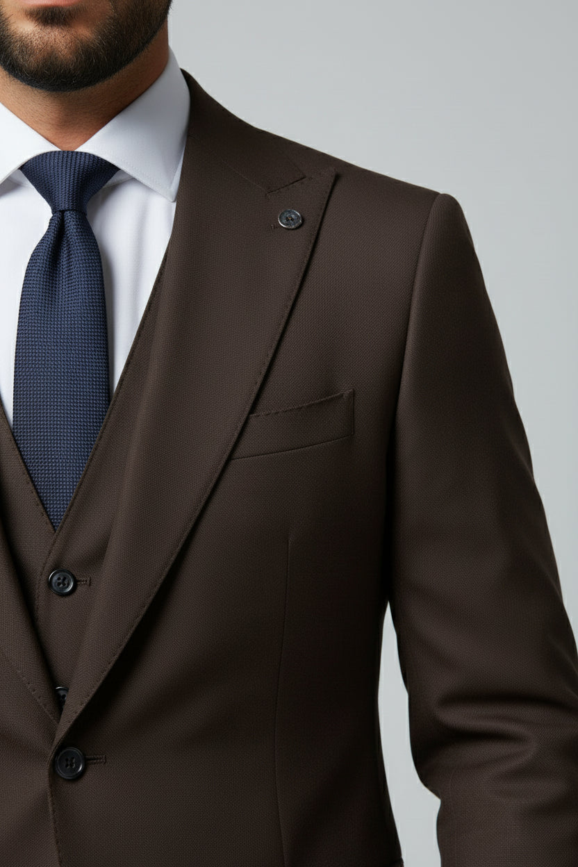 Man wearing brown slim fit three-piece suit with notch lapels and navy tie.