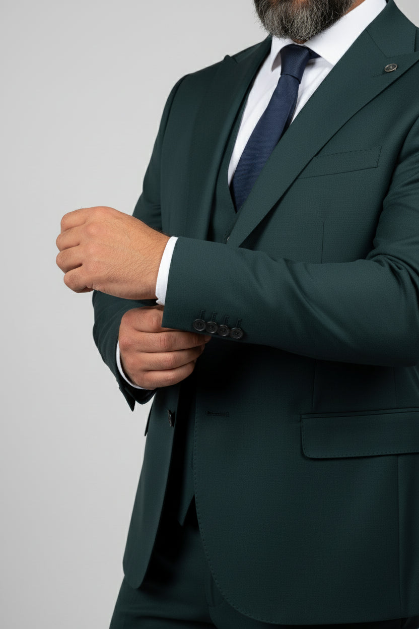 Man adjusting cuff of tailored green three-piece suit with notch lapel.