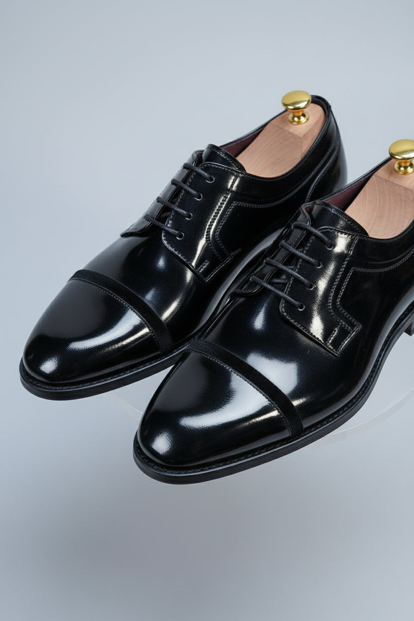Black patent leather dress shoes with lace-up design and classic cap toe style.