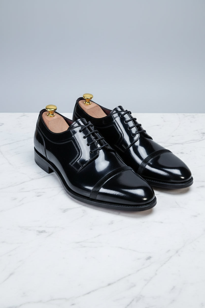 Black patent leather dress shoes with lace-up design and elegant cap-toe detail.