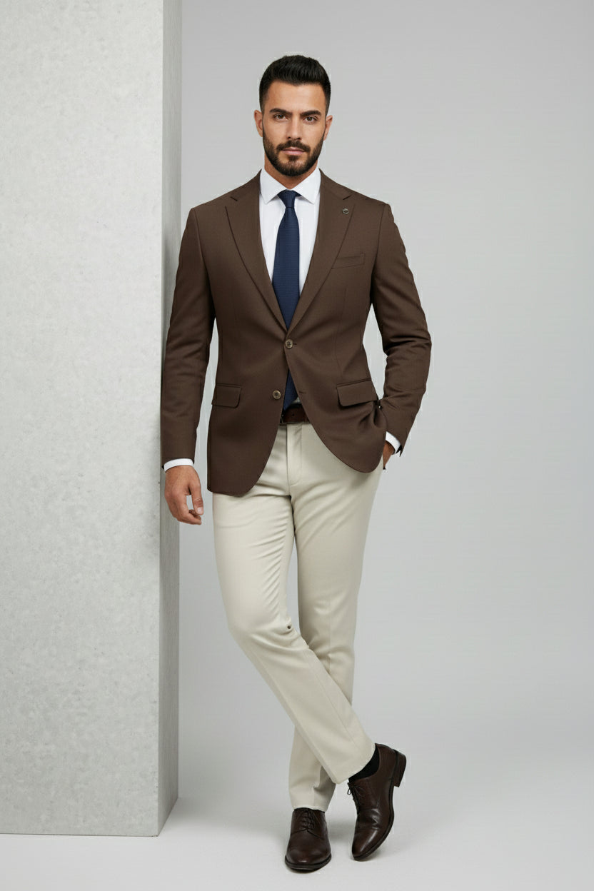 Man in brown and beige slim-fit two-piece suit with navy tie and brown shoes.