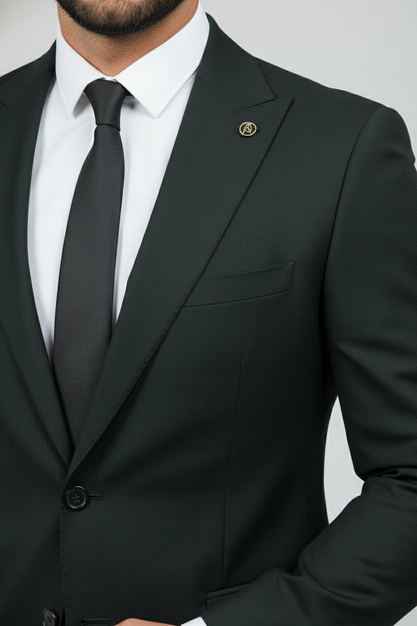 Man wearing dark green tailored two-piece suit with peak lapels and black tie.