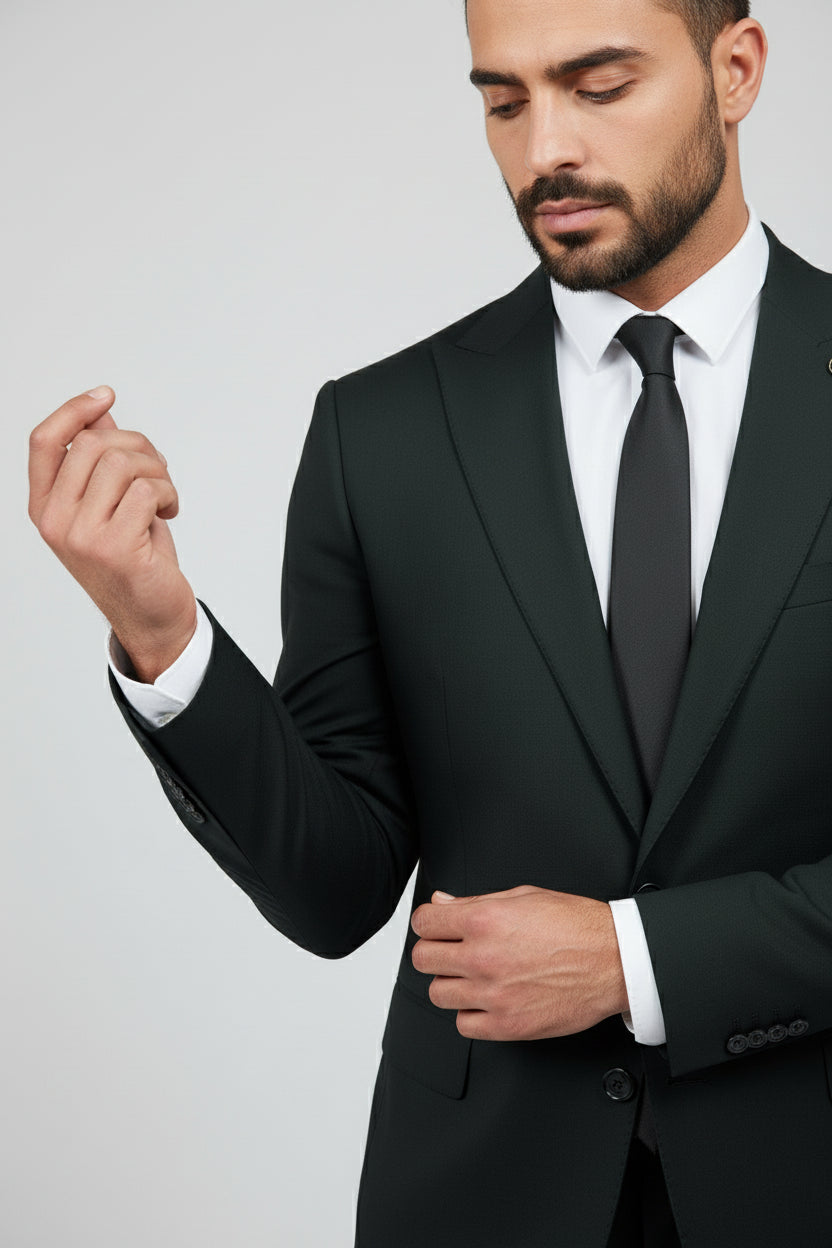 Man adjusting dark green two-piece suit with peak lapels, ideal for formal events.