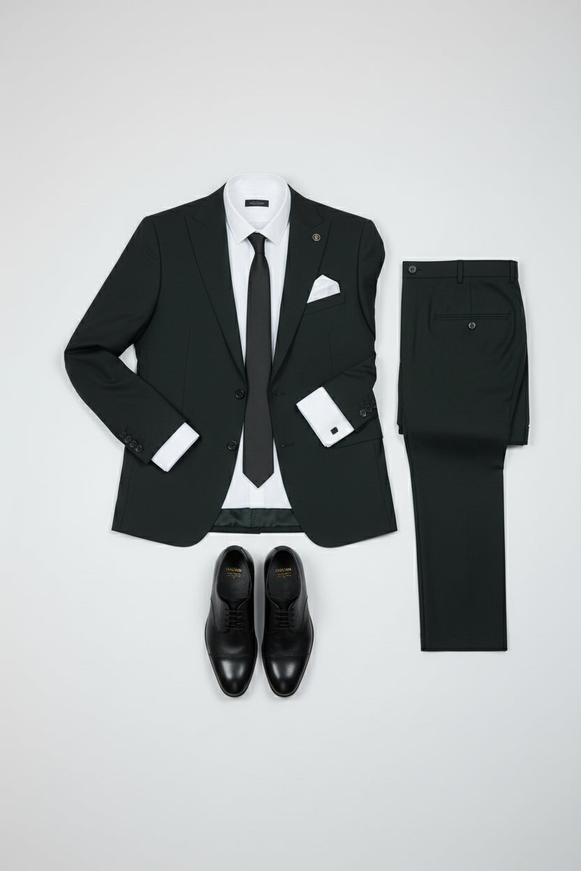 Dark green tailored two-piece suit with peak lapel, paired with black dress shoes.