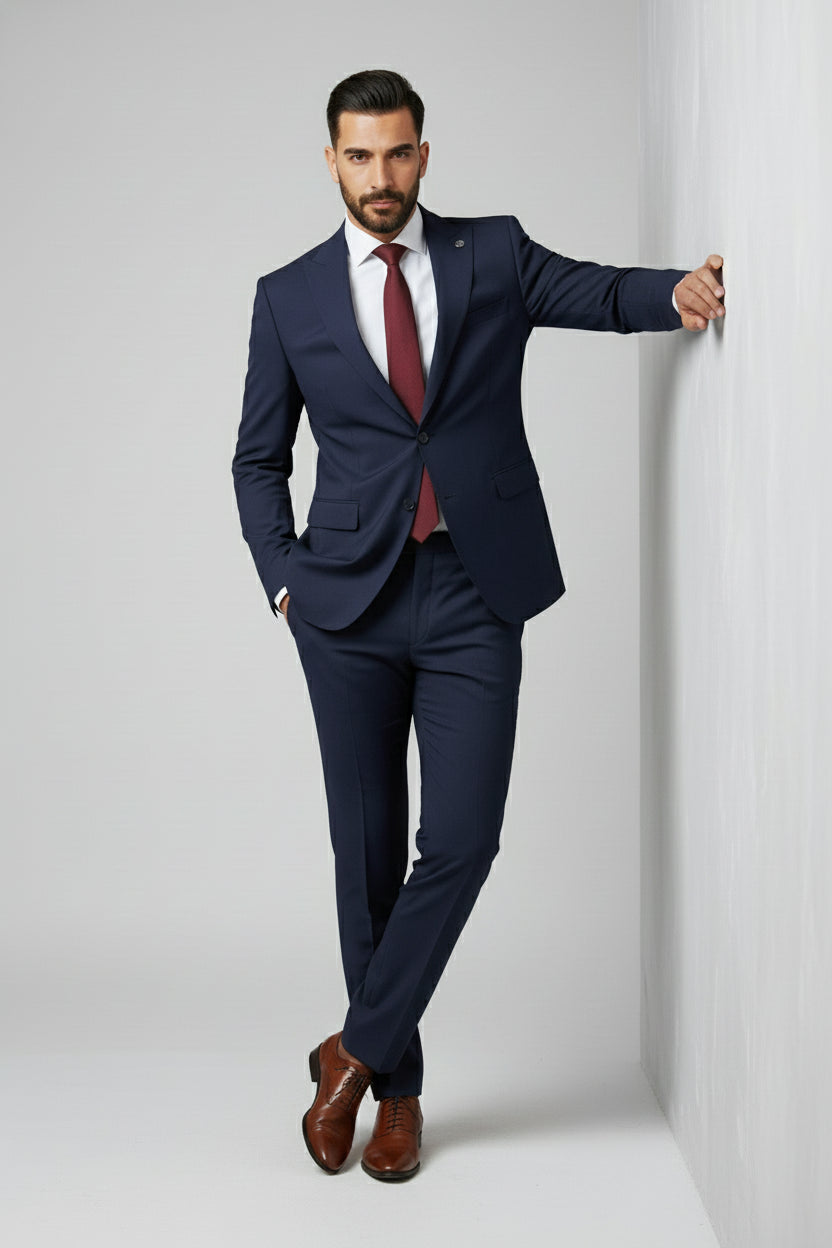 Man in navy two-piece slim-fit suit with peak lapels and burgundy tie.