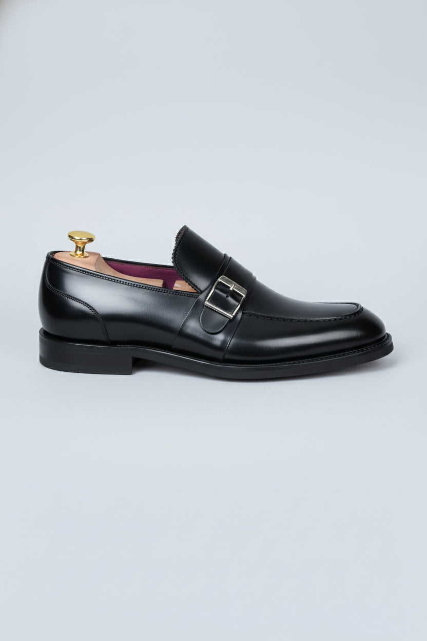 Black leather loafers with silver buckle detail, ideal for formal business wear.