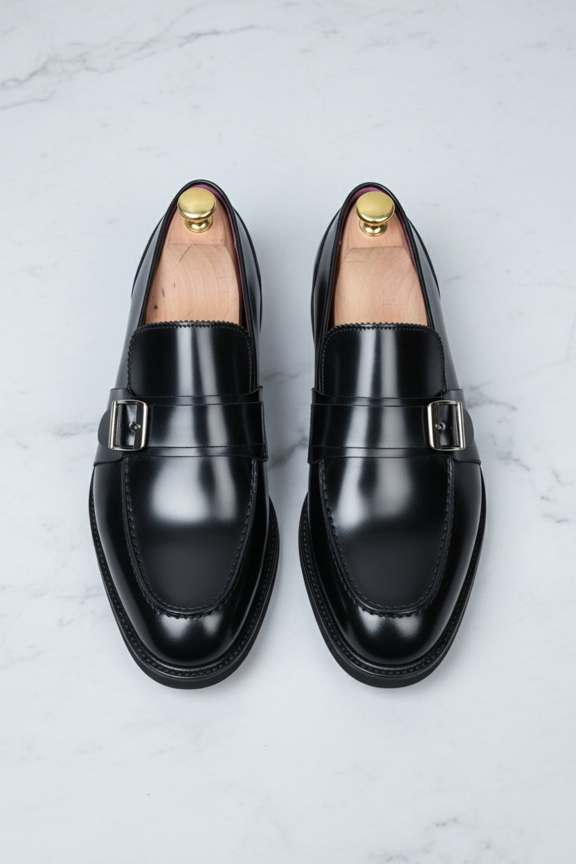 Black leather loafers with silver buckle detail, perfect for formal business attire.
