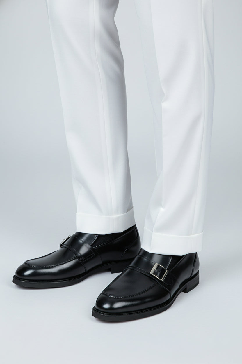 Black leather buckle loafers paired with formal white trousers for an elegant look.