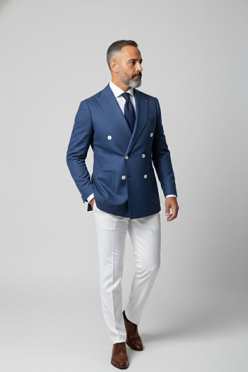 Man wearing a tailored blue double-breasted suit with white trousers for formal events.